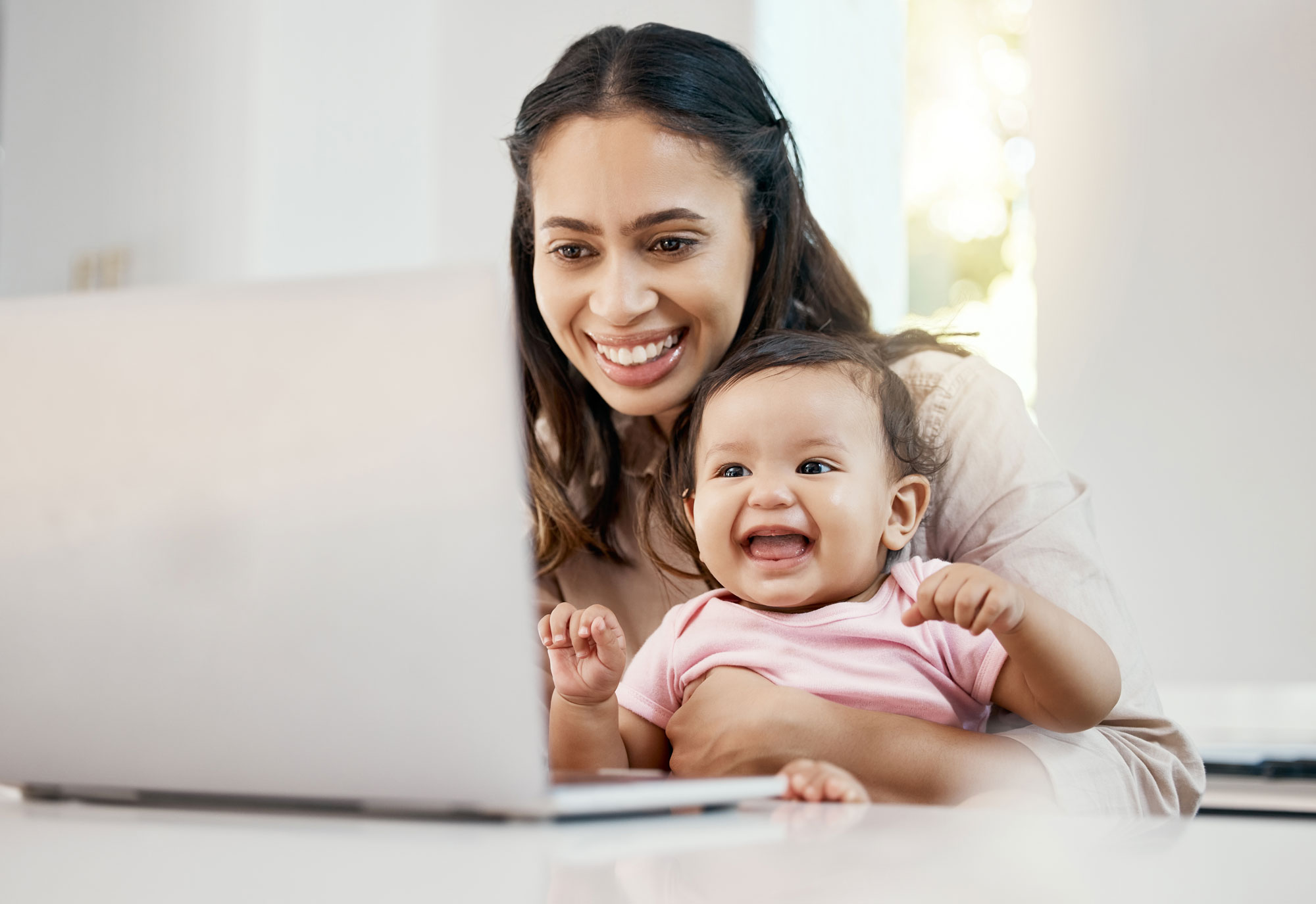 Mom and baby smiling while looking at a computer screen