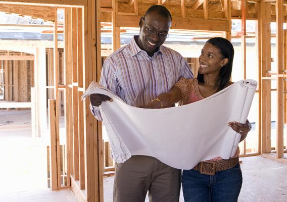 Homebuyers looking over housing blueprints in the construction of new house