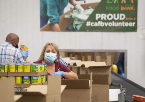 Volunteers packing boxes at a food bank to help