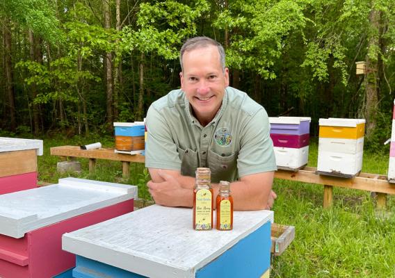 Veteran farmer Jim Hartman in front of his bottles of honey