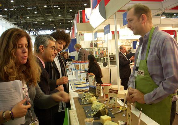 Trade visitors sample a variety of cheeses at the Rogue Creamery stand in the USA Pavilion. Rogue Creamery, an artisan cheese company, is dedicated to sustainability and the art and tradition of making the world's finest handmade cheese.