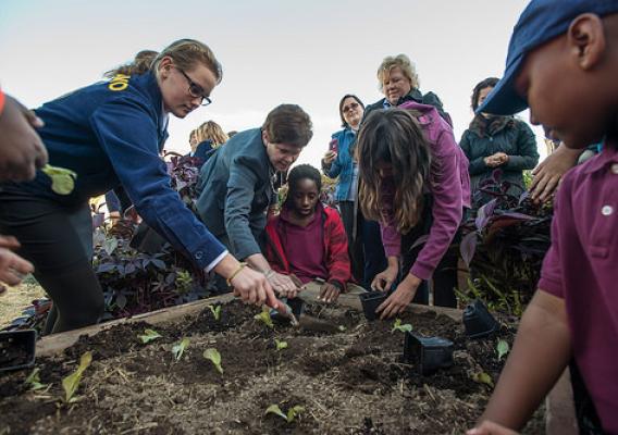 Agriculture Deputy Secretary Krysta Harden (center), helping a Jefferson Middle School student finish up the planting of “Outredgeous Red Romaine Lettuce” in a garden box, in The People's Garden at USDA's Whitten Building.
