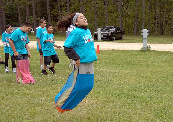 A Menominee girl enjoys the sackrace fun with her classmate friends.