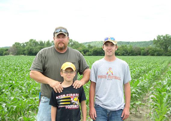 Joe Fillaus and sons, Cole and Carter, standing in front of their June 2013 corn crop after restoration was made to their field. USDA photo.