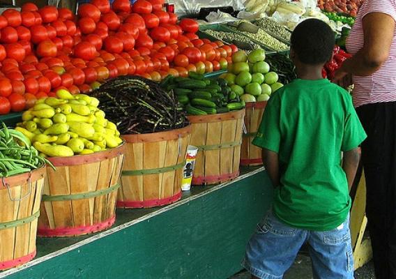 A young boy looking over the fresh fruits and veggies with his mother at a farmers market in Mississippi.