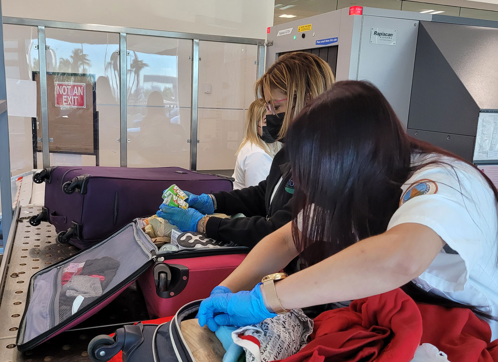 APHIS Plant Protection and Quarantine Predeparture employees in Puerto Rico (Pictured from L to R) Technician Dimarie Rivera and Aid Maria Benitez doing passenger baggage inspections