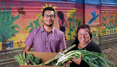 A man and a woman with a variety of fruits and vegetables in a CSA produce box