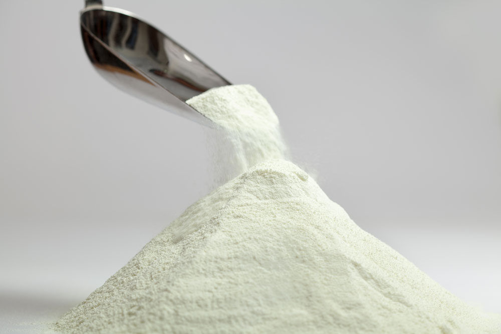 A large spoon pouring a pile of milk powder