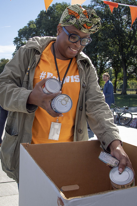 Woman wearing orange donating canned goods at FedsWISH Walk 2022