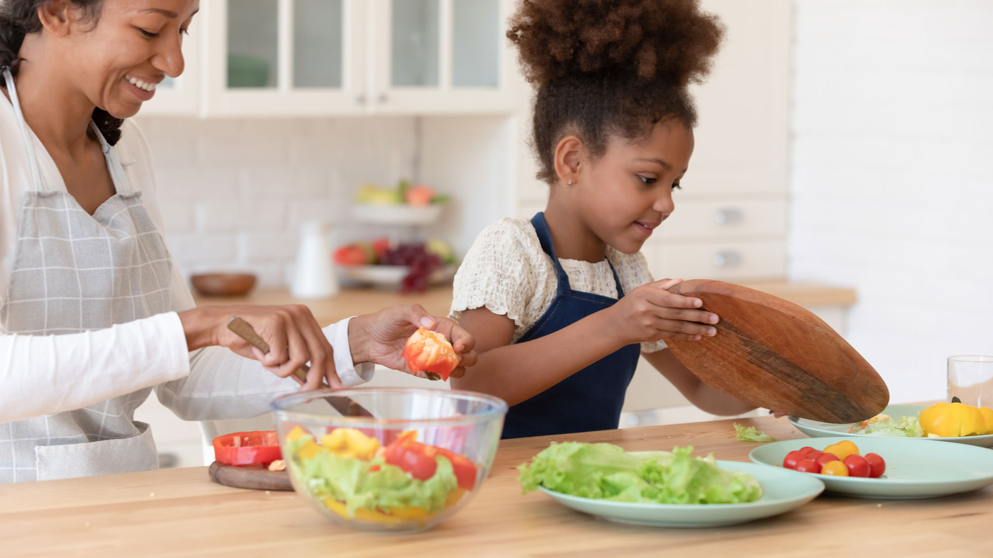 Mother and daughter prepare a healthy meal with chopped vegetables