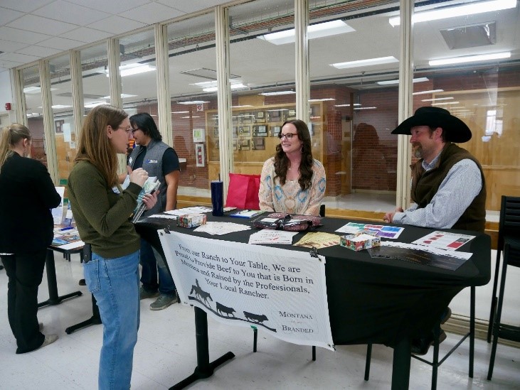 Two beef producers sit at a booth to introduce local school officials to their products during a Farm to School networking event in Hardin, Montana, March 13, 2023