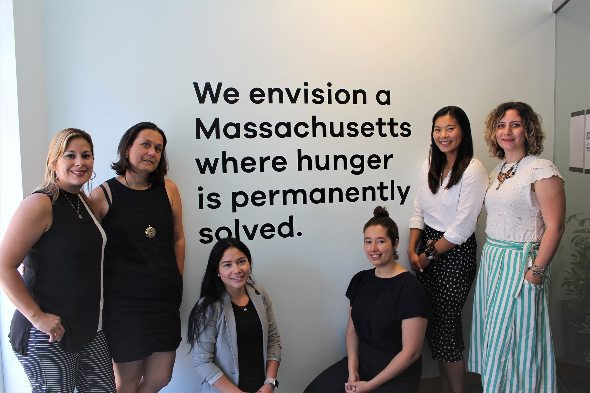 Project Bread’s Flexible Services Program Office Team stands near statement on the wall that reads, “We envision a Massachusetts where huger is permanently solved.”
