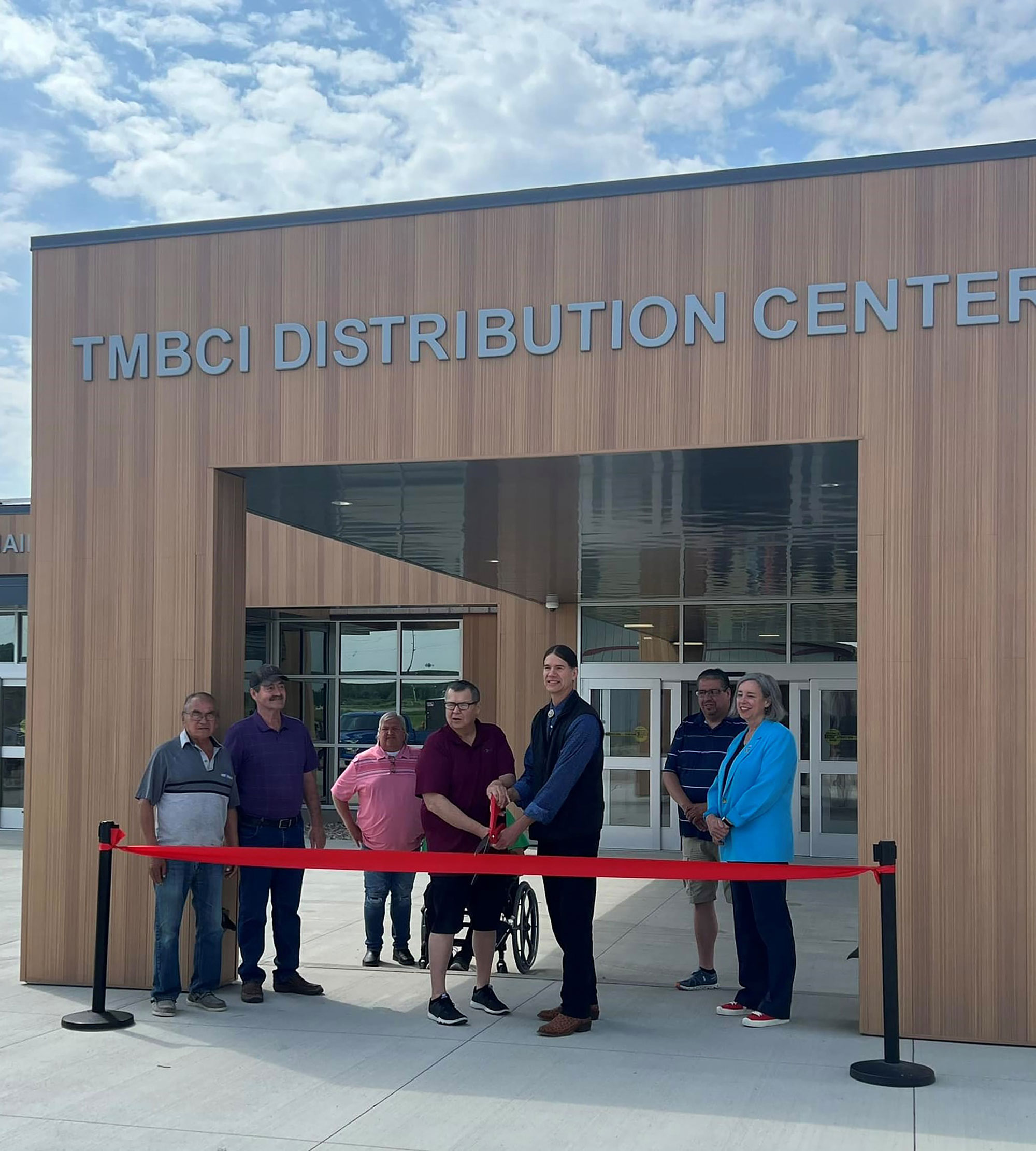 Two men cut red ribbon at the Turtle Mountain Band of Chippewa Indians FDPIR building while FNCS Deputy Under Secretary Stacy Dean and others watch