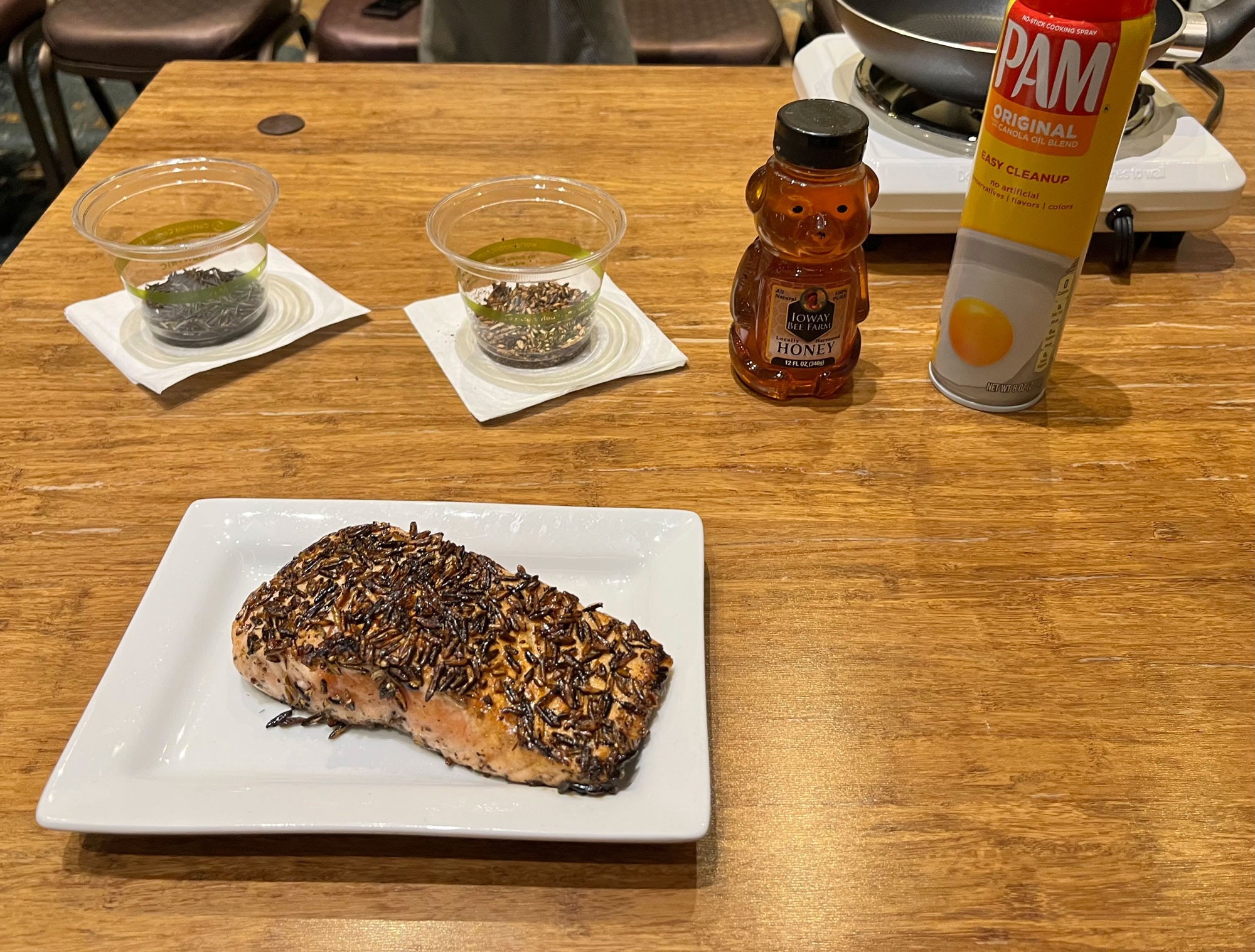 A filet of salmon encrusted in a wild rice coating rests on a white plate