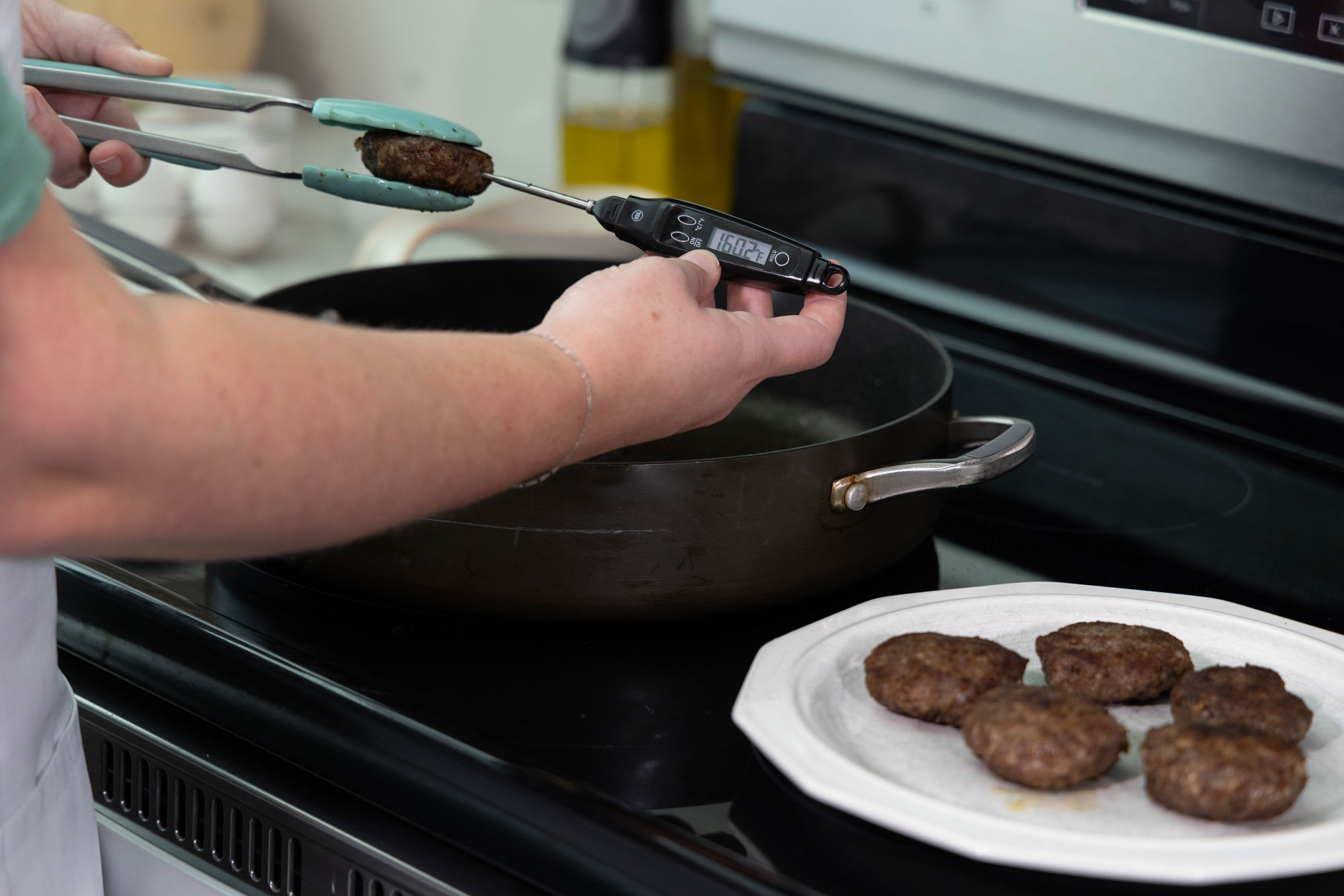 A person inserting a food thermometer into sausage