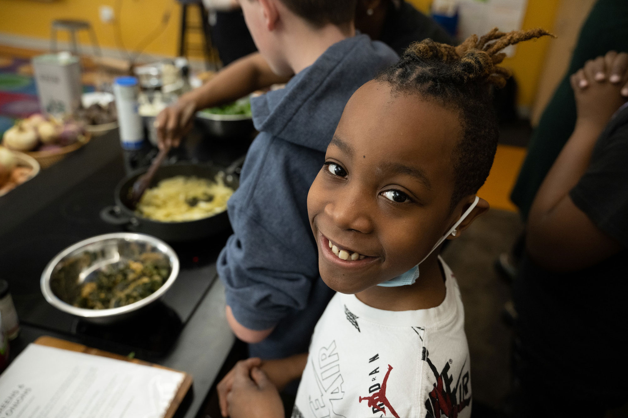 Watkins Elementary School 5th grade student smiles as he learns how to cook collard greens