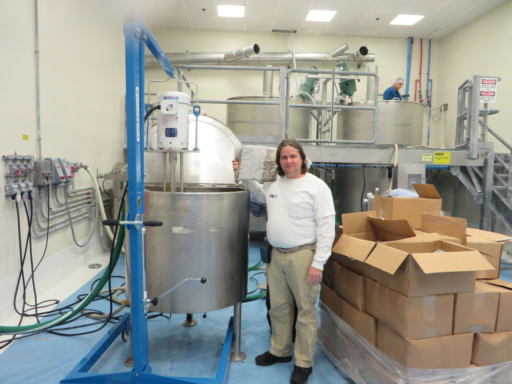 Dr. Aaron Dossey holding the product beside a vat in a facility