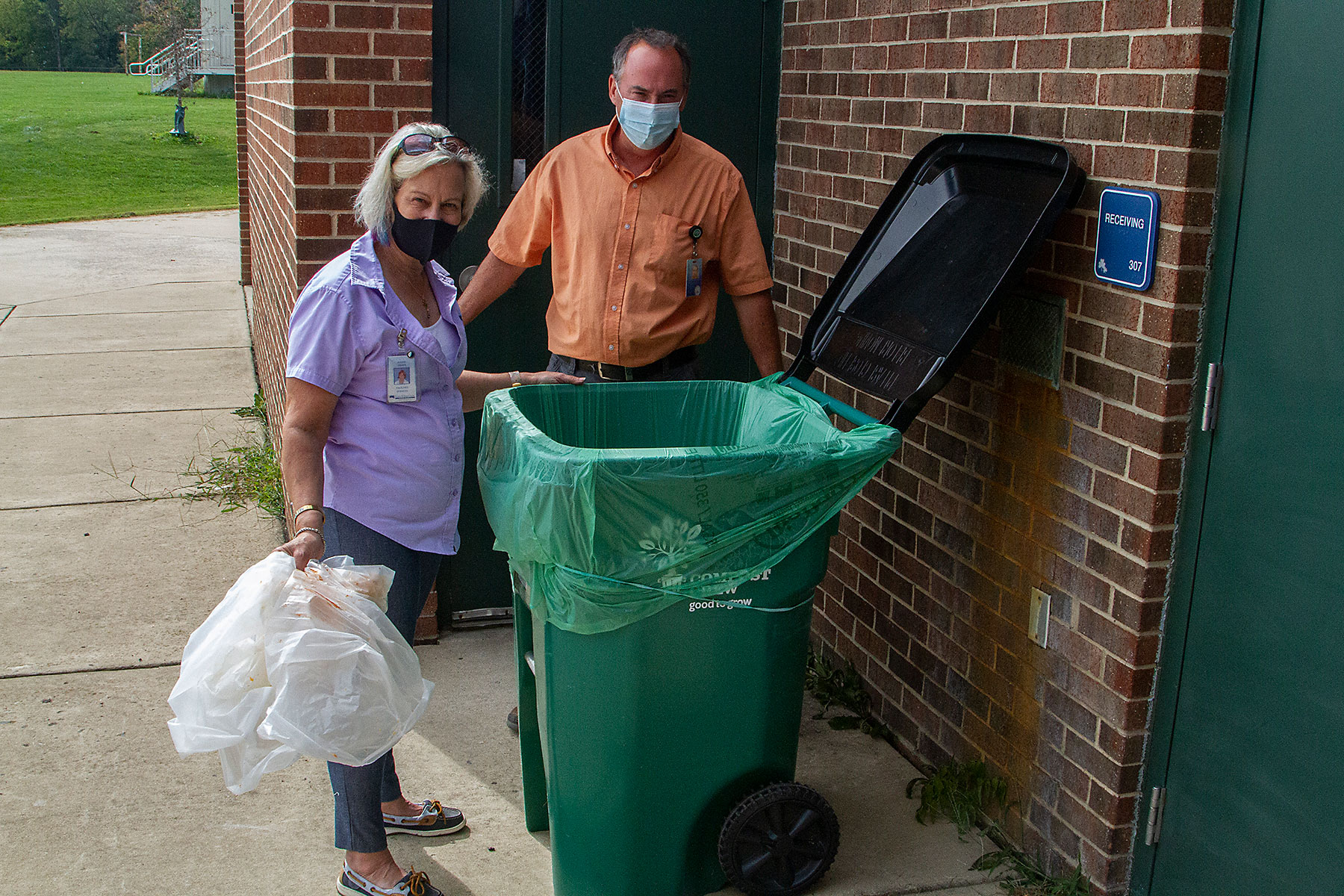 Two people near a compost bag at a school