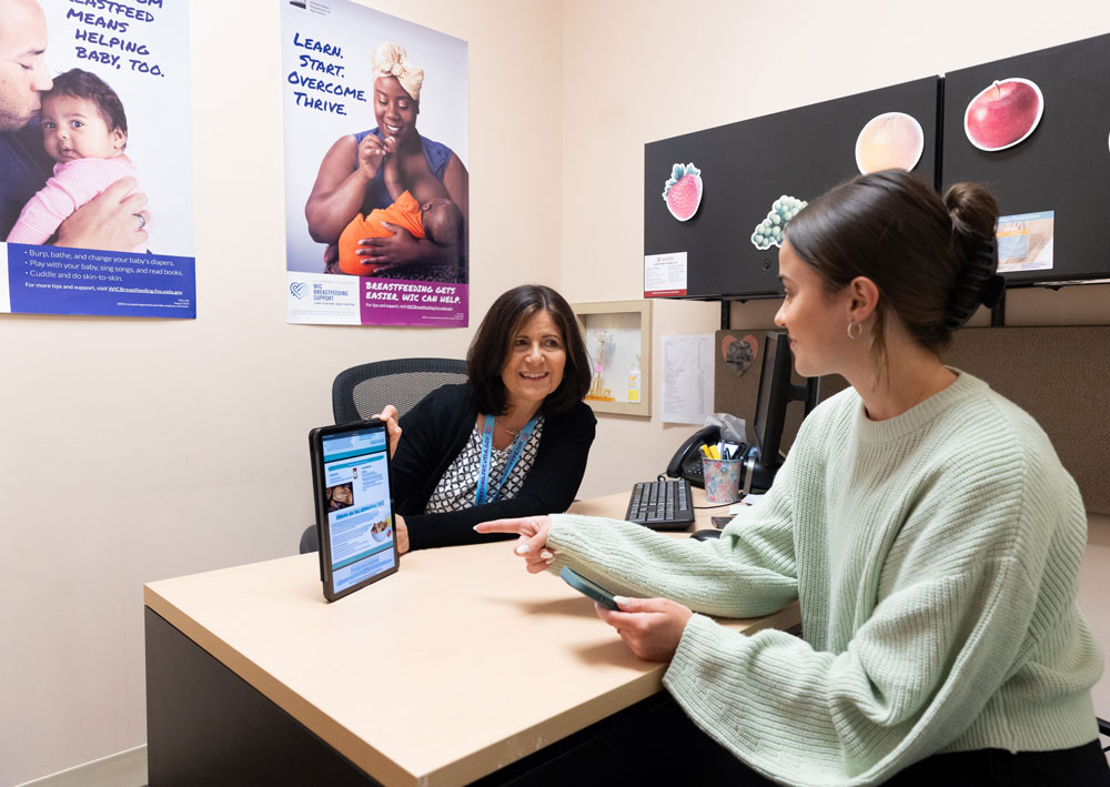 WIC clinic staff discusses nutrition tips with WIC participant using an electronic device at the Access WIC Clinic in Dearborn, Michigan. (June 2023)