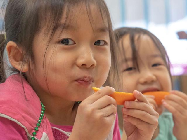 Two girls eating carrots
