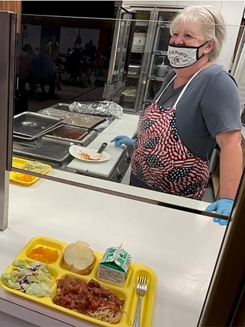 Norma Miller, Prospect Head Cook, serving lunch on a yellow tray with a carton of milk, bread, fruit, salad, and spaghetti