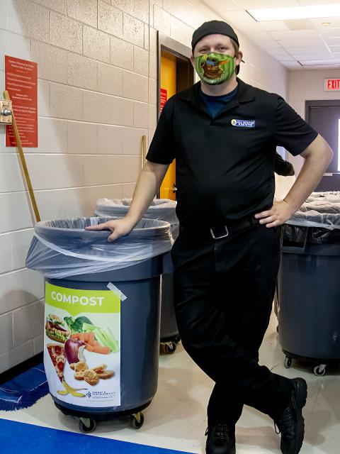 A man standing beside compost cans
