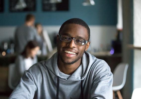 Portrait of smiling African American student looking at camera sitting in cafe