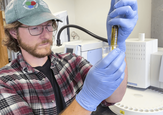 ARS microbiologist, Kevin Panke-Buisse inspects the two-chambered vial filed with milk, indicator dye, and a urease enzyme