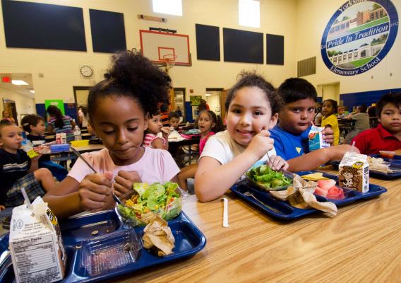 Four elementary school students eat lunch in a school cafeteria
