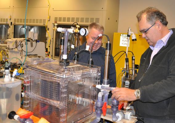 In a lab, CEO of Pancopia Inc, Research partner Bill Cumbie, CEO of Pancopia, Inc., (left) and Matias Vanotti, soil scientist from the Agricultural Research Service, inspect a prototype space bioreactor using anammox