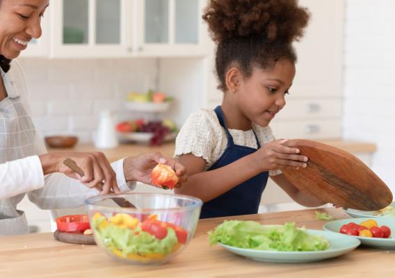 Mother and daughter prepare a healthy meal with chopped vegetables
