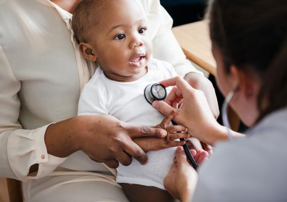 A medical provider uses a stethoscope to listen to a baby’s heartbeat
