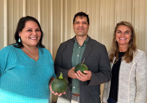 Jessika Free-Bass and Mario Ramos hold garden produce and stand with Cheryl Kennedy
