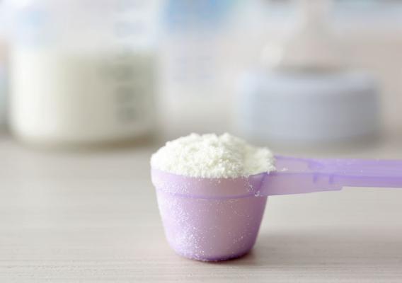 Baby milk formula in purple spoon on wooden background