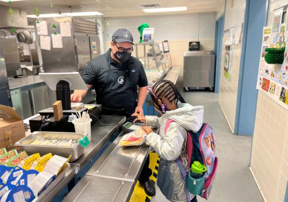 Student receives breakfast from school meal professional in the school kitchen