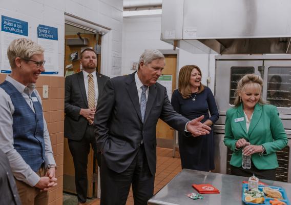 Danielle Bock, Greeley Evans Director of Nutrition Services; Melissa Rothstein, USDA Associate Administrator for Child Nutrition; Dr. Deirdre Pilch, Greeley Evans Superintendent and Secretary Tom Vilsack observe a school meal tray in the Maplewood Elementary School kitchen
