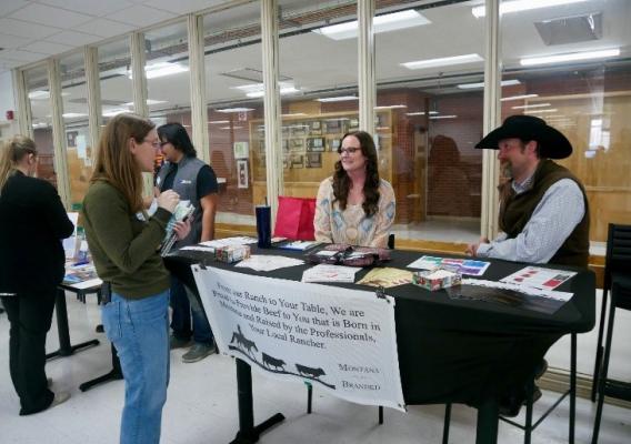 Two beef producers sit at a booth to introduce local school officials to their products during a Farm to School networking event in Hardin, Montana, March 13, 2023