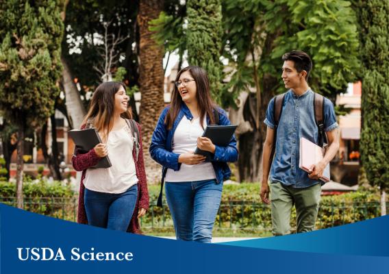 College students walking on campus carrying books. Image courtesy of Adobe Stock.