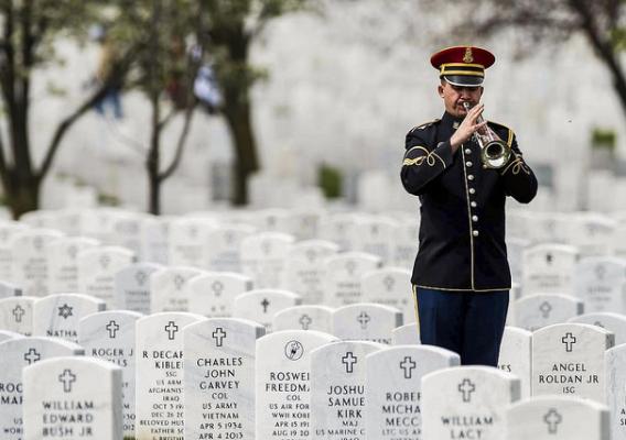 A lone Army bugler playing taps during an interment at Arlington National Cemetery