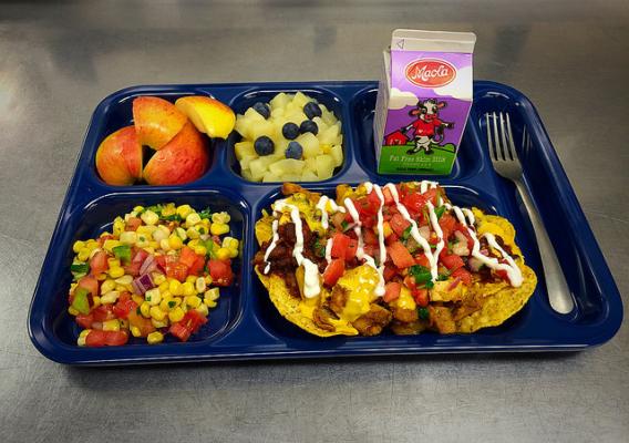 A tray with fruits, vegetables, milk and nachos