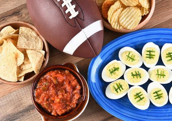 Super Bowl foods and a football on a wooden table