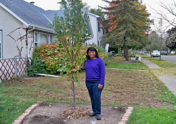 Frogtown homeowner Renee Taylor stands proudly next to her newly planted tree thanks to the tree planting partnership. (U.S. Forest Service/Teri Heyer)