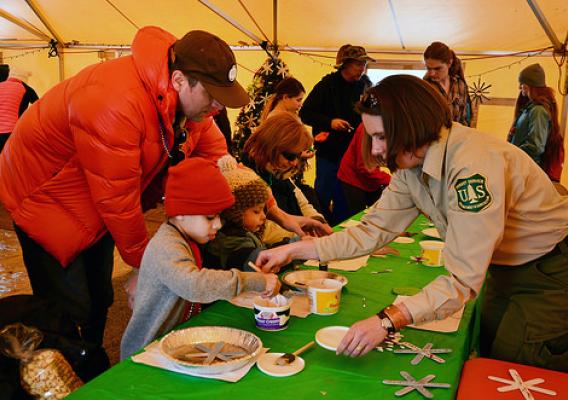 U.S. Forest Service employee Cheyenne Warner helping children make ornaments that will adorn the 2016 U.S. Capitol Christmas Tree