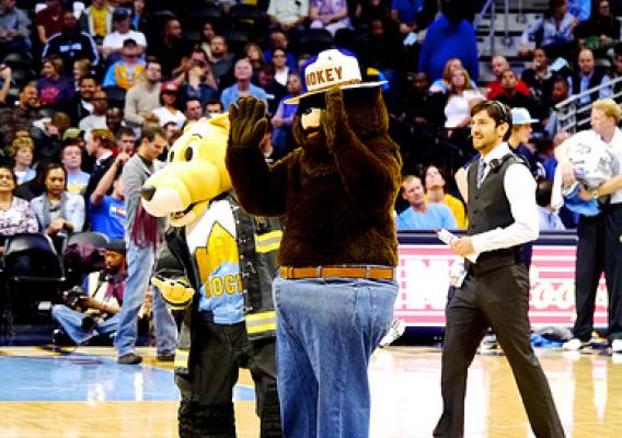 Smokey waves to the crowd at the pre-season opener with Nuggets mascot Rocky at center court. (U.S. Forest Service/Todd Riecks)