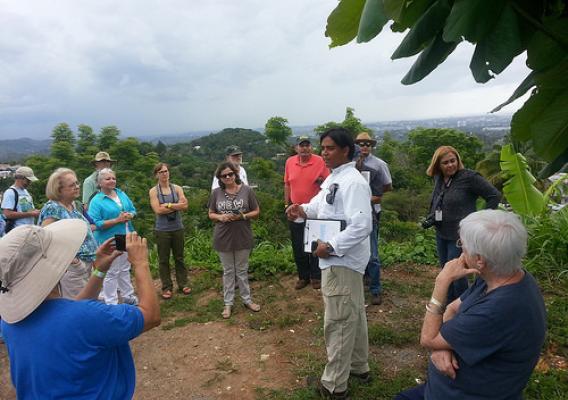 Ray Rodriguez, a collaborator from Para la Naturaleza, talks about the rural-urban ecotone and positive outcomes of community action as participants enjoy a birds-eye view overlooking the Río Piedras River Watershed boundaries in the San Juan metropolitan area, the final stop of an urban field trip on May 20 held as part of the Institute’s 75th anniversary celebration. (U.S. Forest Service)