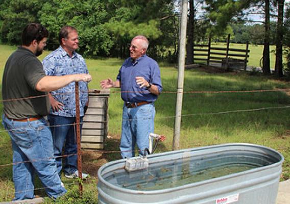 Ryan Witt, NRCS soil conservationist, Kelvin Burge, Hancock County Soil and Water Conservation District conservation technician, and Johnny Williams, Hancock County rancher, discuss the benefits of the solar powered well. NRCS photo.