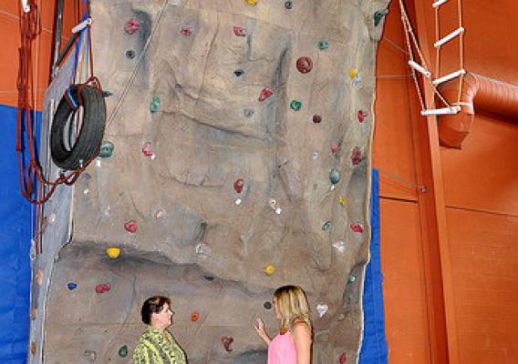 A climbing wall at Rimrock Trails Adolescent Treatment Services is one of many tools available to help troubled teens build their self-esteem. Pictured are State Director Vicki Walker (left) and Rimrock Trails’ Residential Mental Health Counselor Courtney Parchmon.  Rimrock Trails employs 30 professionals dedicated to helping some of our most vulnerable adolescents.