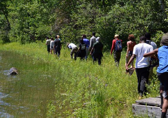 A group of young people from Detroit walk a somewhat unfamiliar path along the shoreline of Clear Lake on the Hiawatha National Forest in Michigan. The U.S. Forest Service teams with partners to help open the world of natural resources to children who live in cities. (U.S. Forest Service)