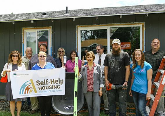 USDA Rural Development State Director Vicki Walker (center with wheelbarrow), U.S. Representative Suzanne Bonamici (center with level), local nonprofit Community Action Team (CAT), and community leaders with first-time homeowners Jessica and Jason Smith