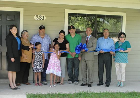 The Reanna Fernandez family proudly cuts a ribbon symbolic of starting their new life in a home they helped construct.  (State Director Paco Valentin is third from the right.)  